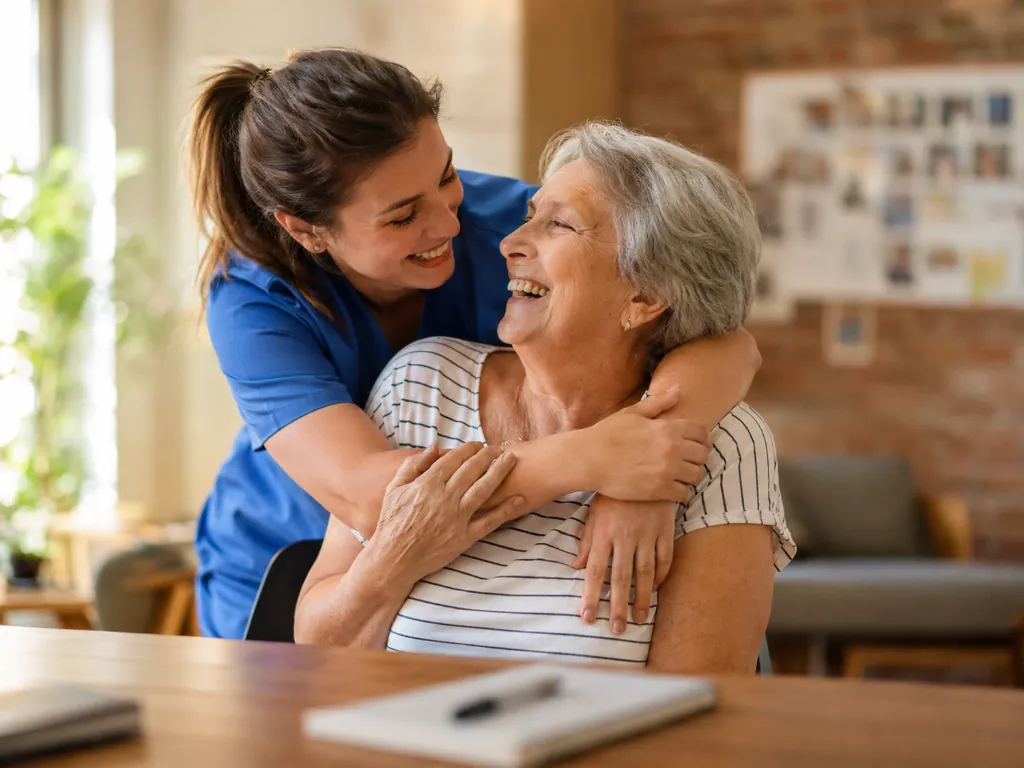 A caregiver embracing an older woman at home