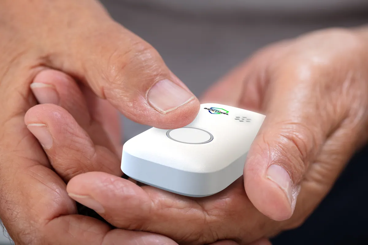 An older person holding the Sentinel Pulse, thumb resting on the help button