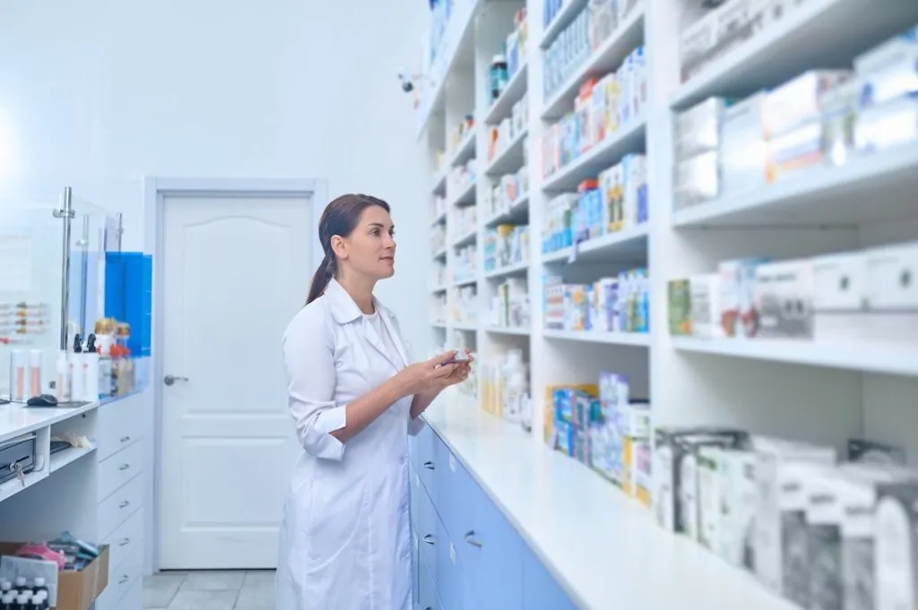 A pharmacist reviewing medication on a pharmacy shelf
