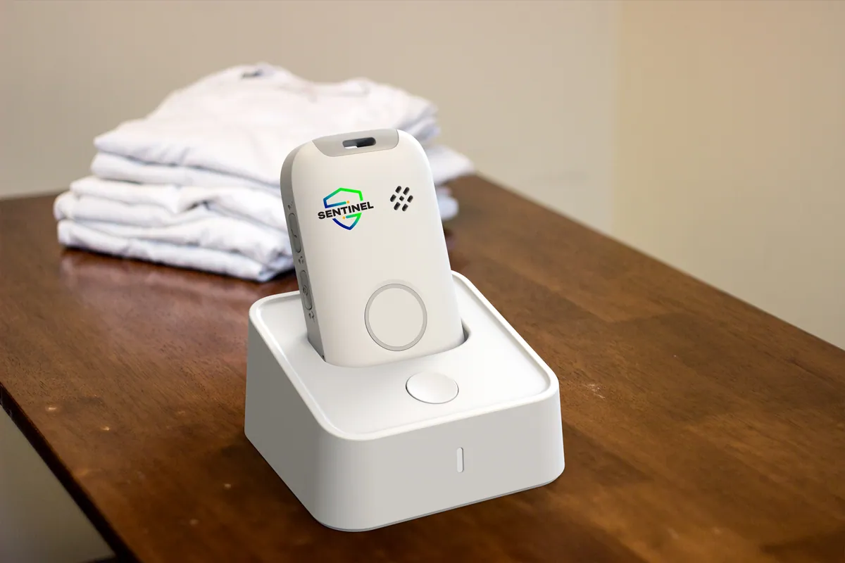 A Sentinel Pulse charging in its dock on a bedroom dresser